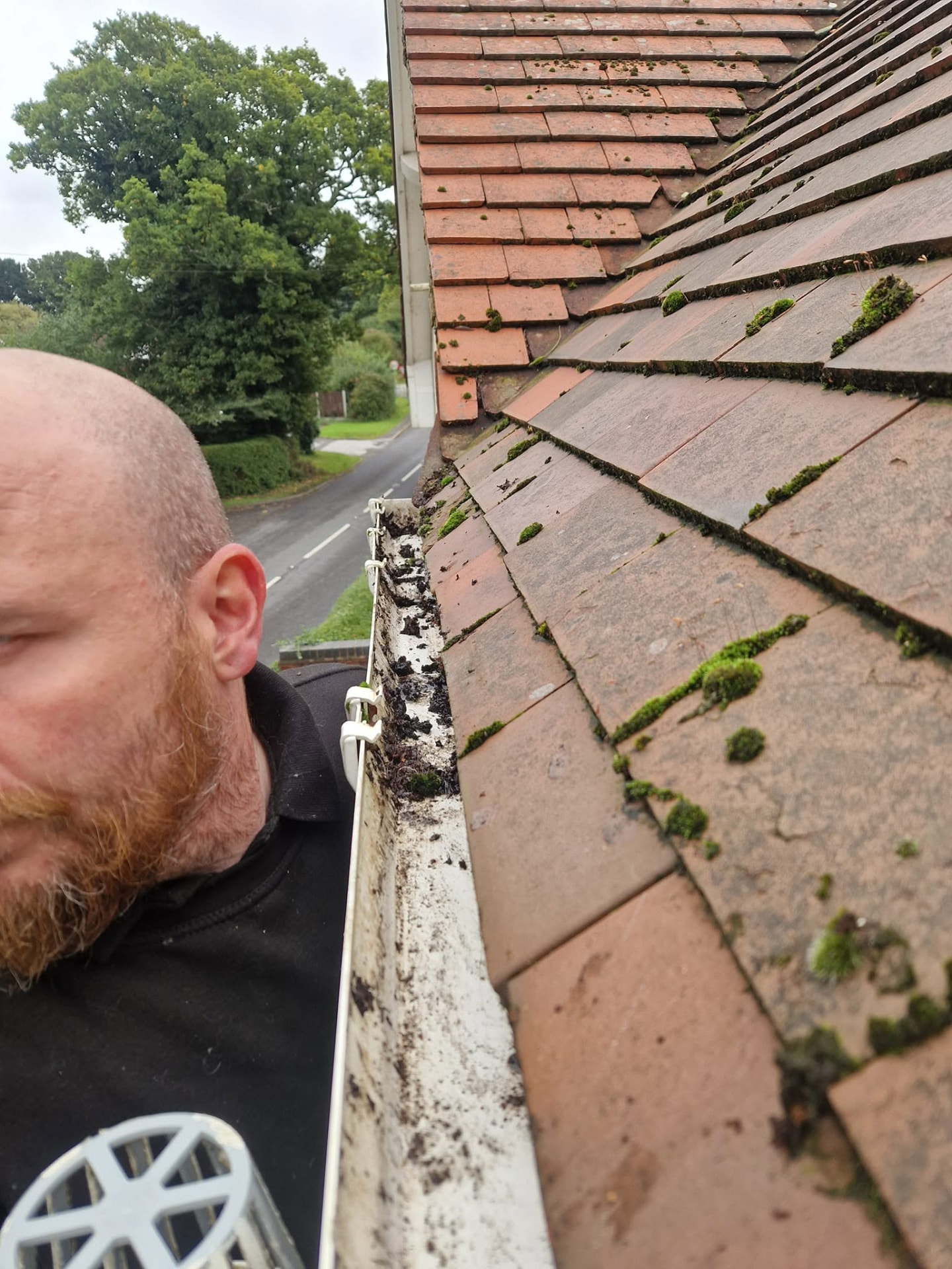Gutter clearance removing moss and debris from a house gutter in Redditch, Worcestershire