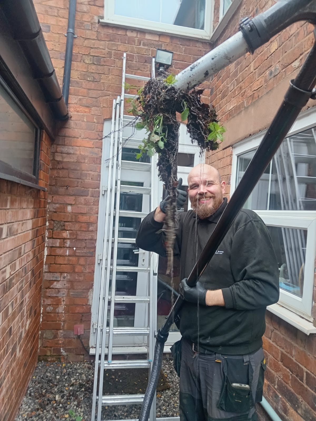 Gutter clearance removing moss and debris from a house gutter in Redditch, Worcestershire